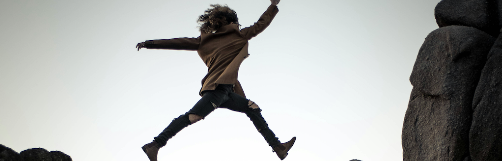 Woman jumping over boulders