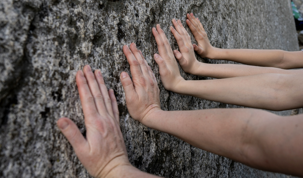Team with all their hands on a rock